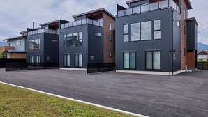 Un edificio residencial moderno con techo plano, ventanas grandes y un espacio exterior cubierto.