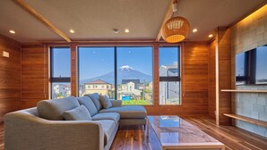 Un salón moderno con sofá, mesa de centro y amplios ventanales con vistas a la montaña.