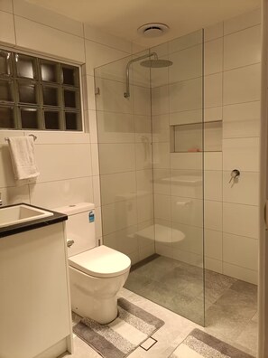 Enjoy a refreshing shower in the sleek bathroom with a glass-enclosed shower, toilet, and vanity.
