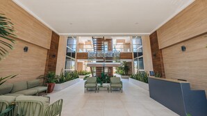 Eine großzügige Lobby mit einer zentralen Treppe, einer Sitzecke und Topfpflanzen.