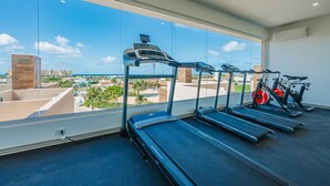 Ein Fitnessstudio mit Laufbändern und Ergometer, großen Fenstern mit Stadtblick und modernem Design.