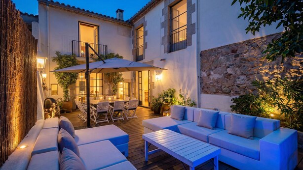Un patio con zona de comedor, asientos exteriores y un muro de piedra.