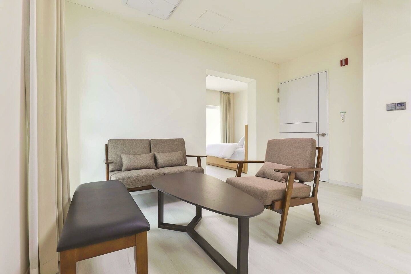 A room with a sofa, a chair, a small table, and a bed.
