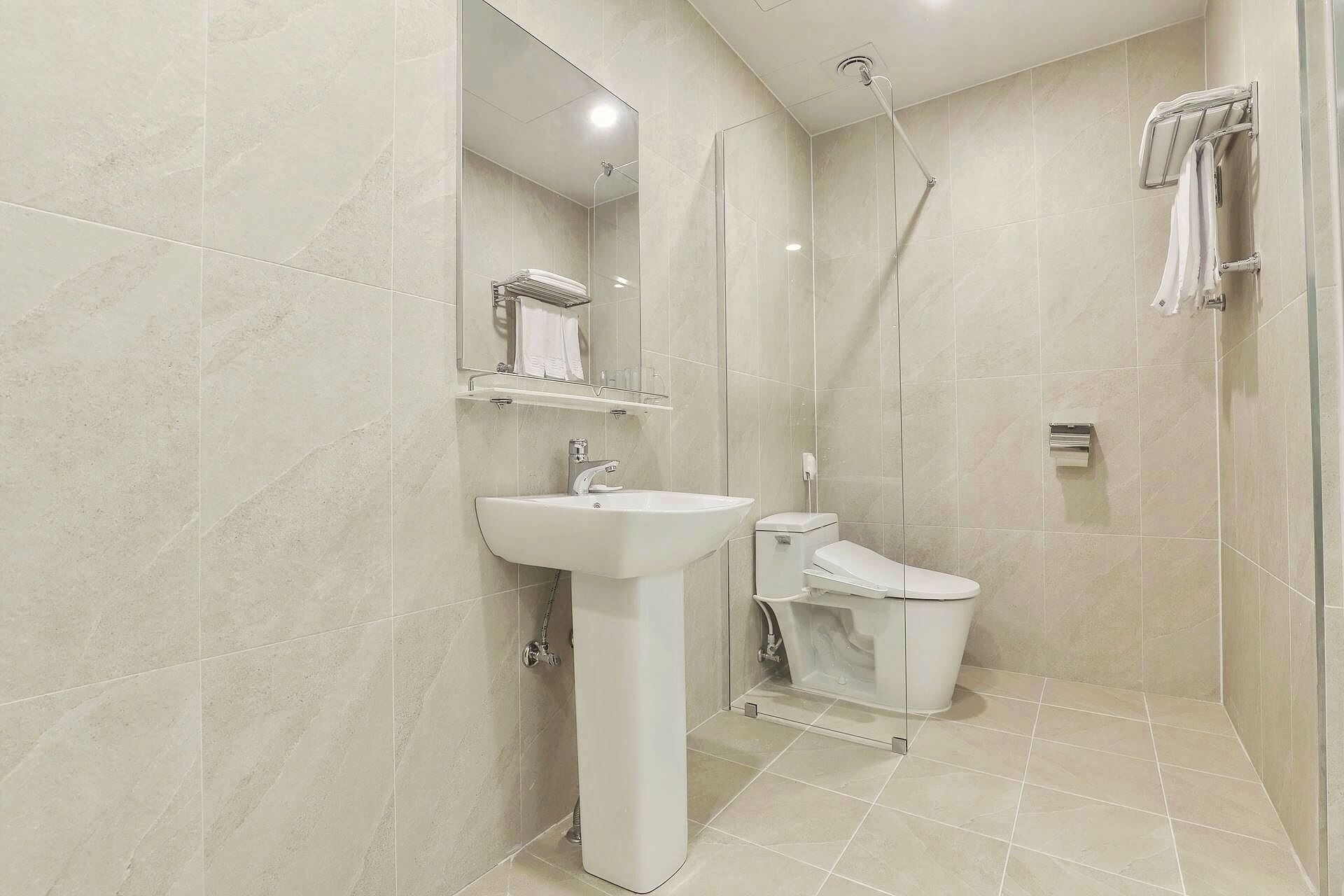 A modern bathroom with a pedestal sink, toilet, and shower.