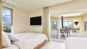 A hotel room with two beds, a TV, and a balcony with a table and chairs. - Hotel BERITH (Sokcho)