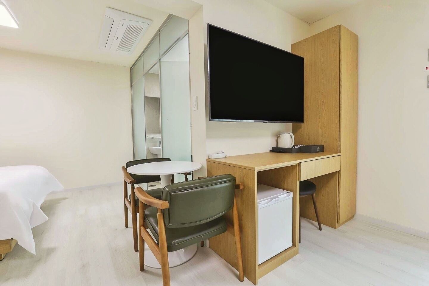 A hotel room with a bed, a desk, a chair, a television, and a mirror.