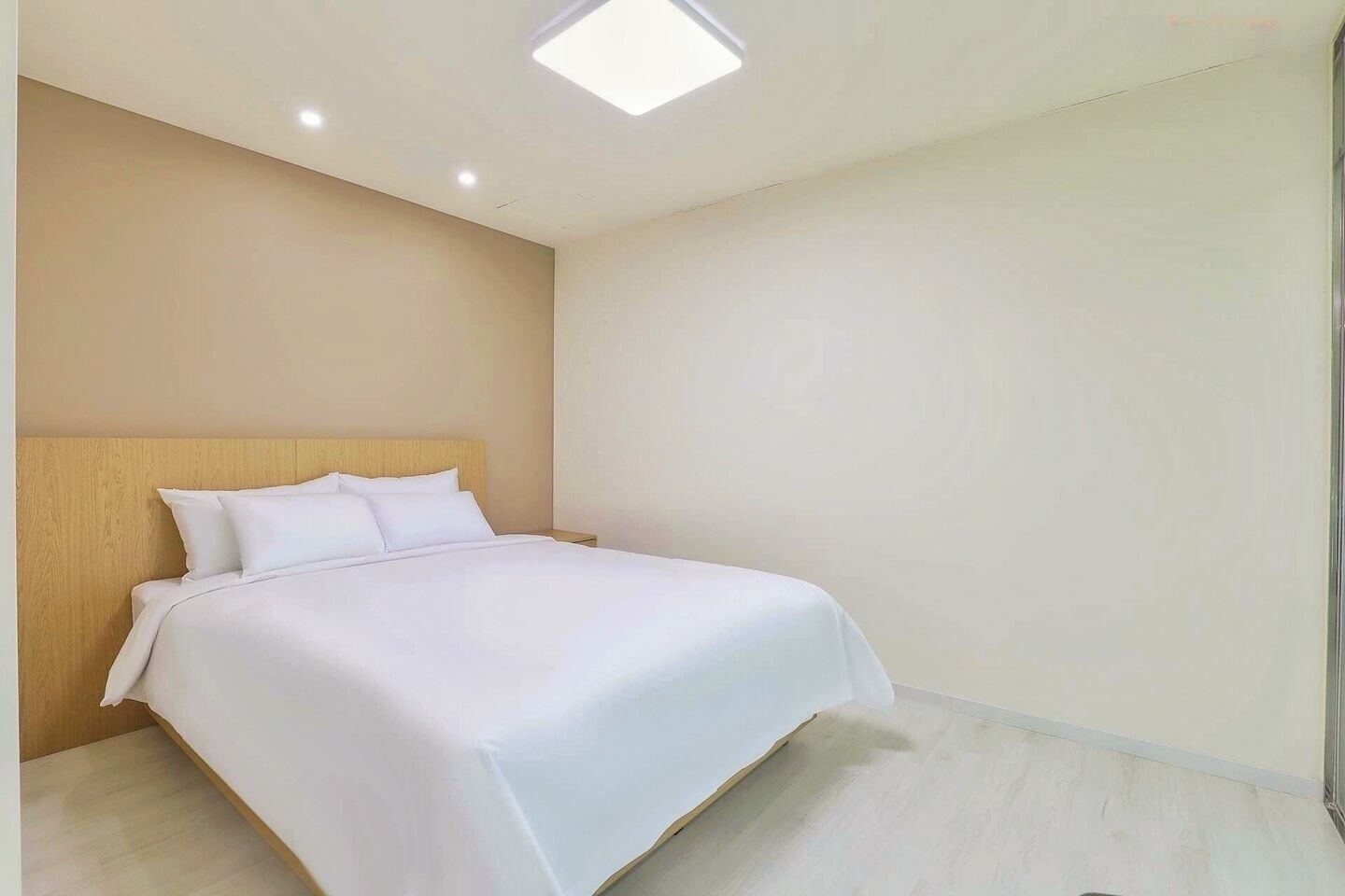Une chambre d’hôtel avec un lit, une tête de lit en bois et un plancher de couleur claire.