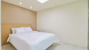 A hotel room with a bed, wooden headboard, and a light-colored floor.