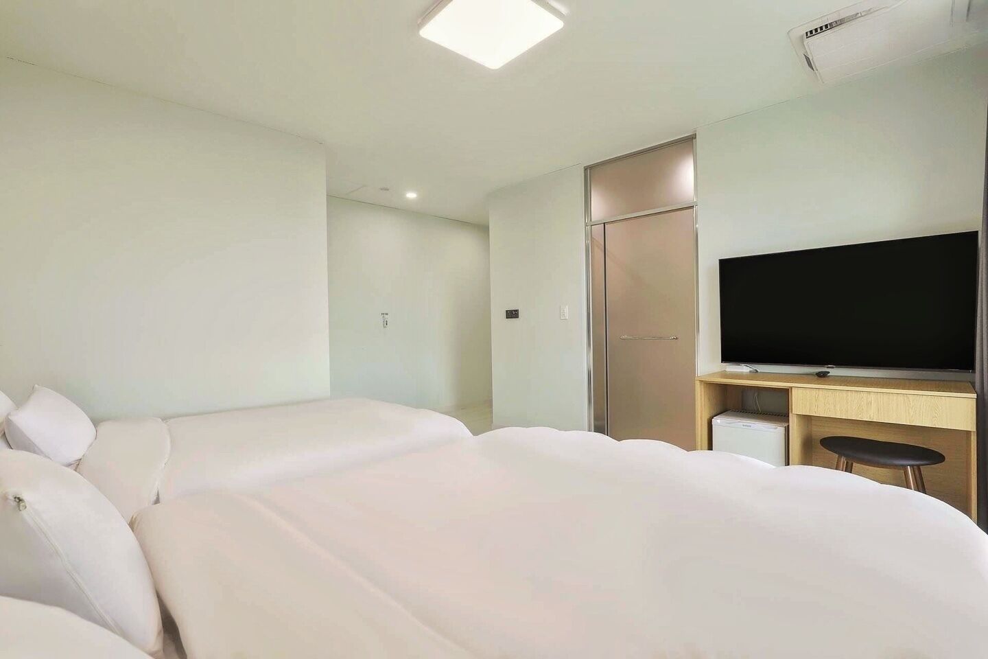 A hotel room with two beds, a TV, a desk, and a wardrobe.