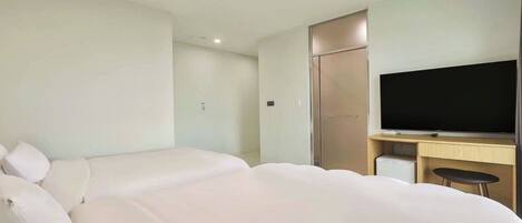 A hotel room with two beds, a TV, a desk, and a wardrobe.