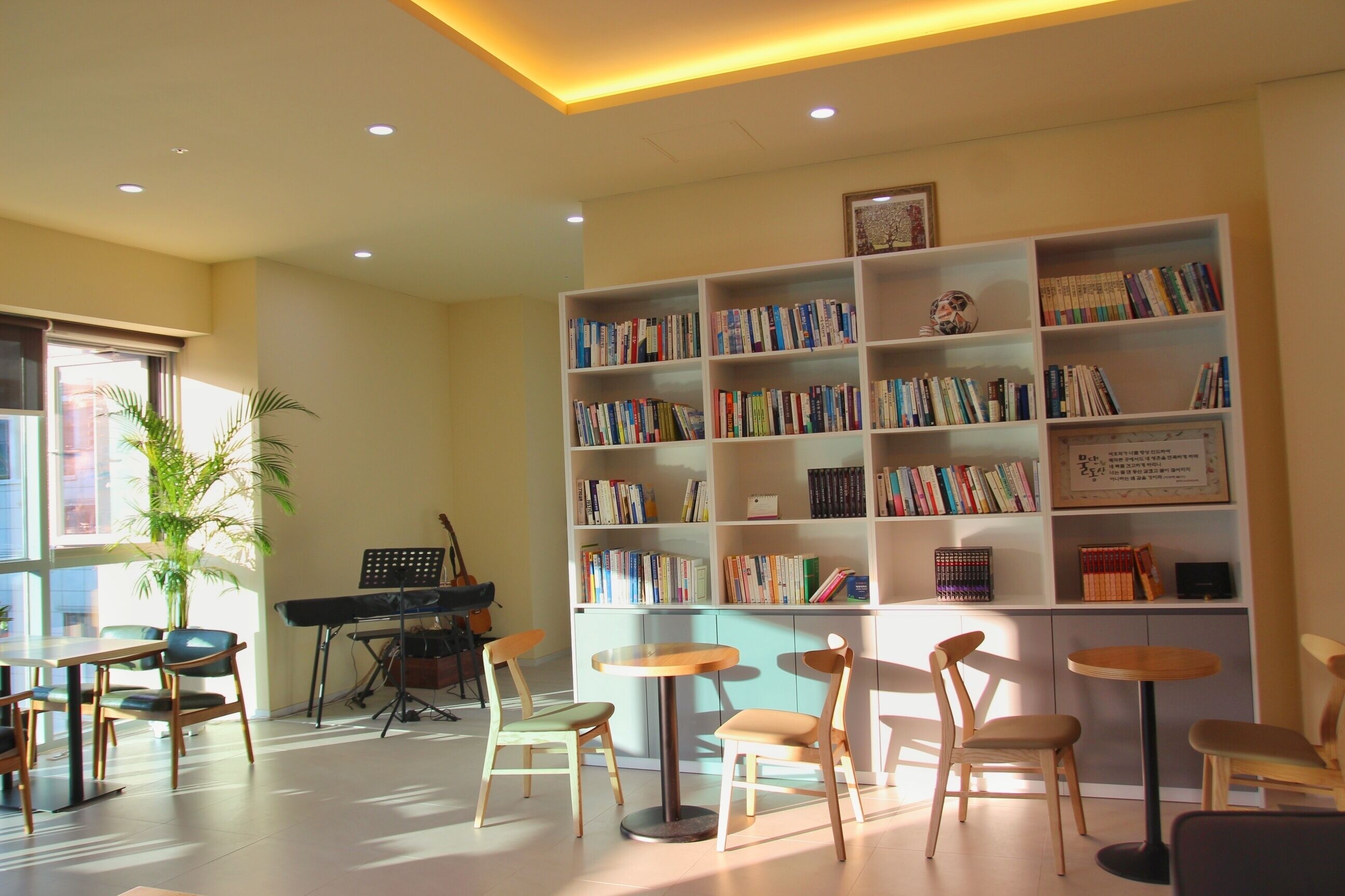 A library with bookshelves, a piano, and seating areas.