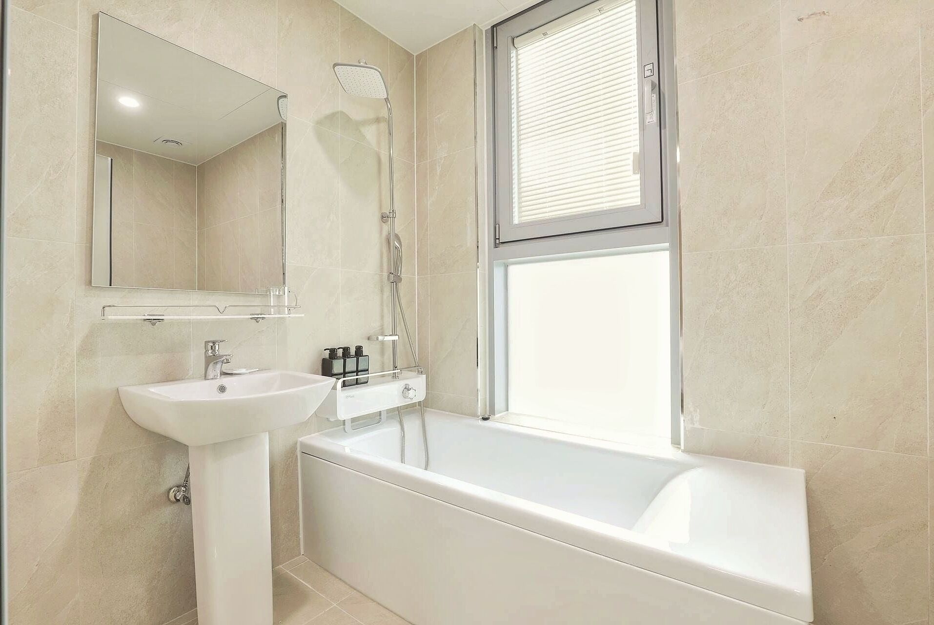 Une salle de bain moderne avec une baignoire, un lavabo sur colonne et un grand miroir.