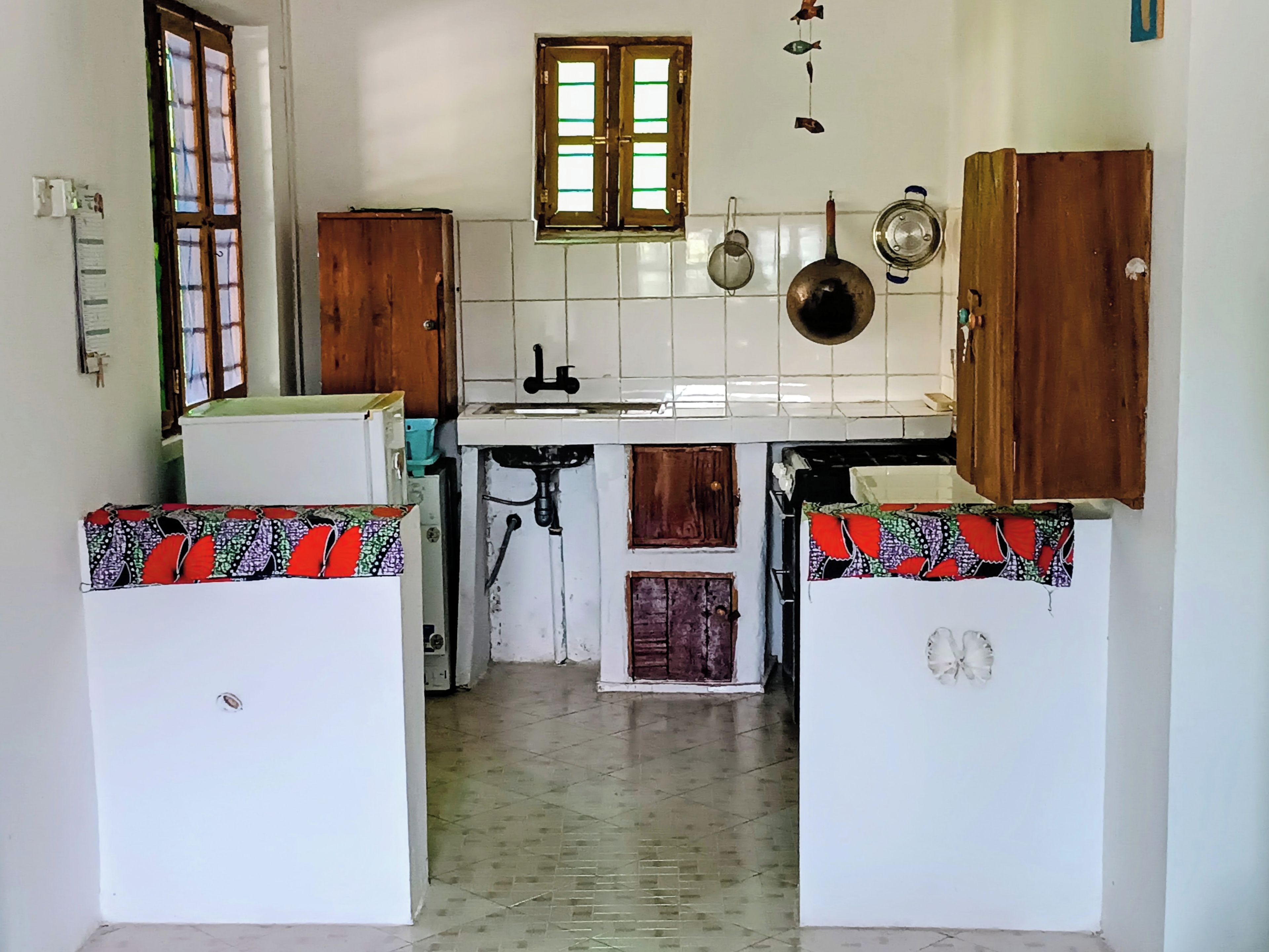 A compact kitchen with white cabinets, a window, and a tiled floor.