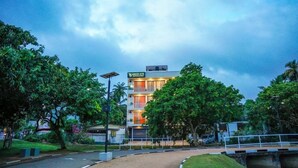 Un hotel con un letrero que dice 'GREEN EYE', rodeado de exuberante vegetación y un cielo despejado.