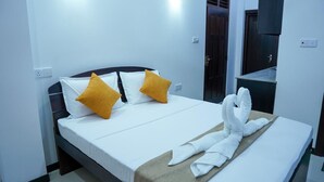 Habitación de hotel con una cama, dos almohadas, una mesita de noche y una puerta.