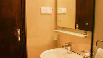 A bathroom with a wooden door, a white sink, a mirror, and a light fixture above the mirror.