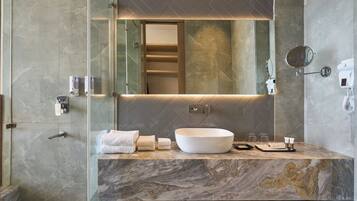 A modern bathroom with a large mirror, a white vessel sink, and marble countertops.