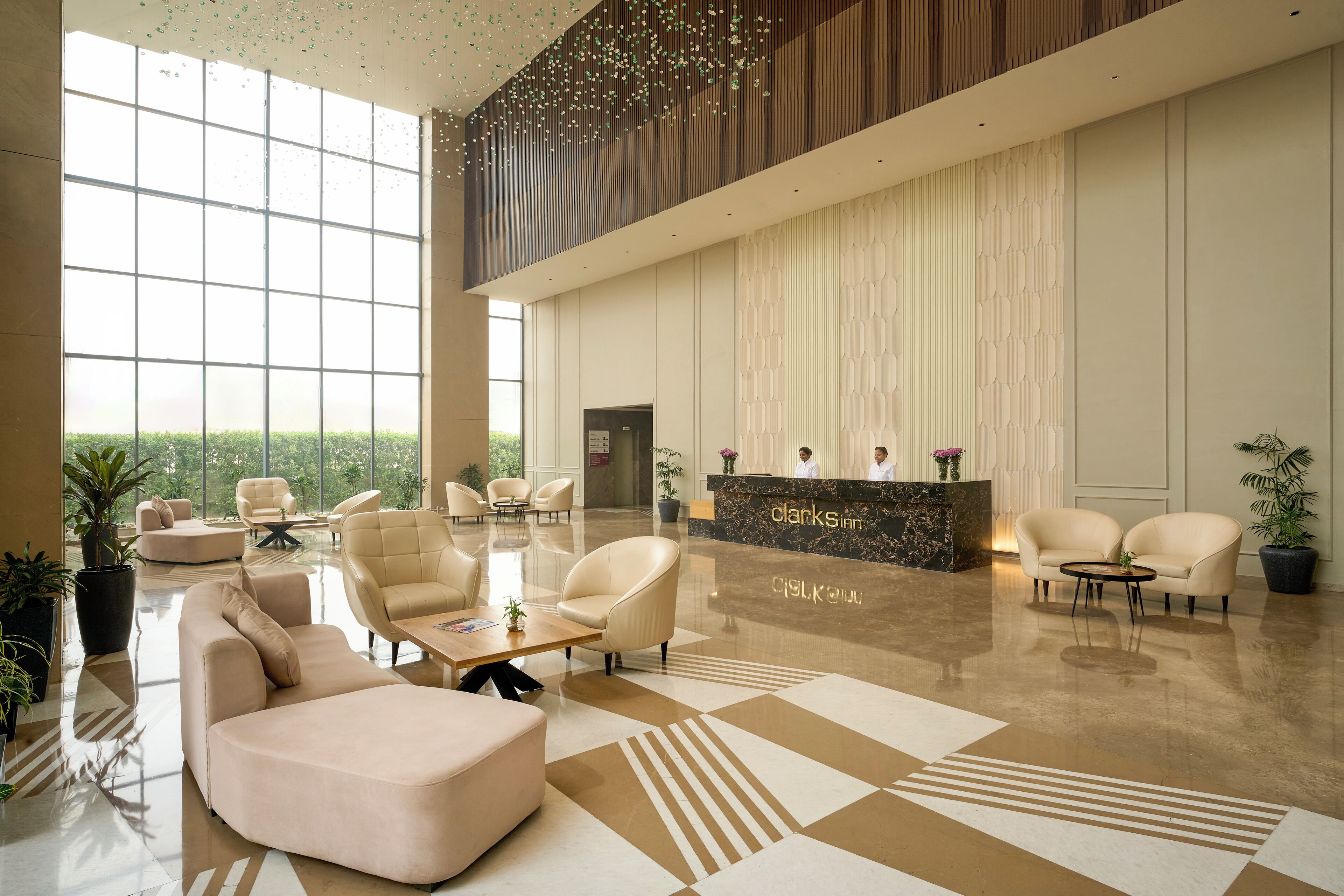 Eine großzügige Lobby mit einer Rezeption, Sitzbereichen und großen Fenstern mit Blick auf Grünflächen.