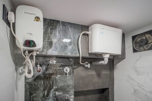 Une salle de bain avec un mur en marbre noir, un chauffe-eau blanc et un ventilateur blanc.