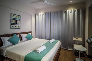 Une chambre d’hôtel avec un lit, des oreillers, une chaise, un bureau et un rideau.