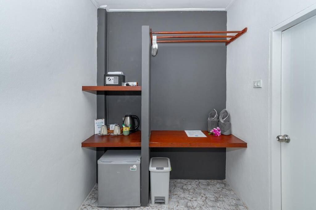 Uma casa de banho compacta com uma pia cinzenta, um pequeno contentor de lixo, um porta-toalhas e uma máquina de café numa prateleira.
