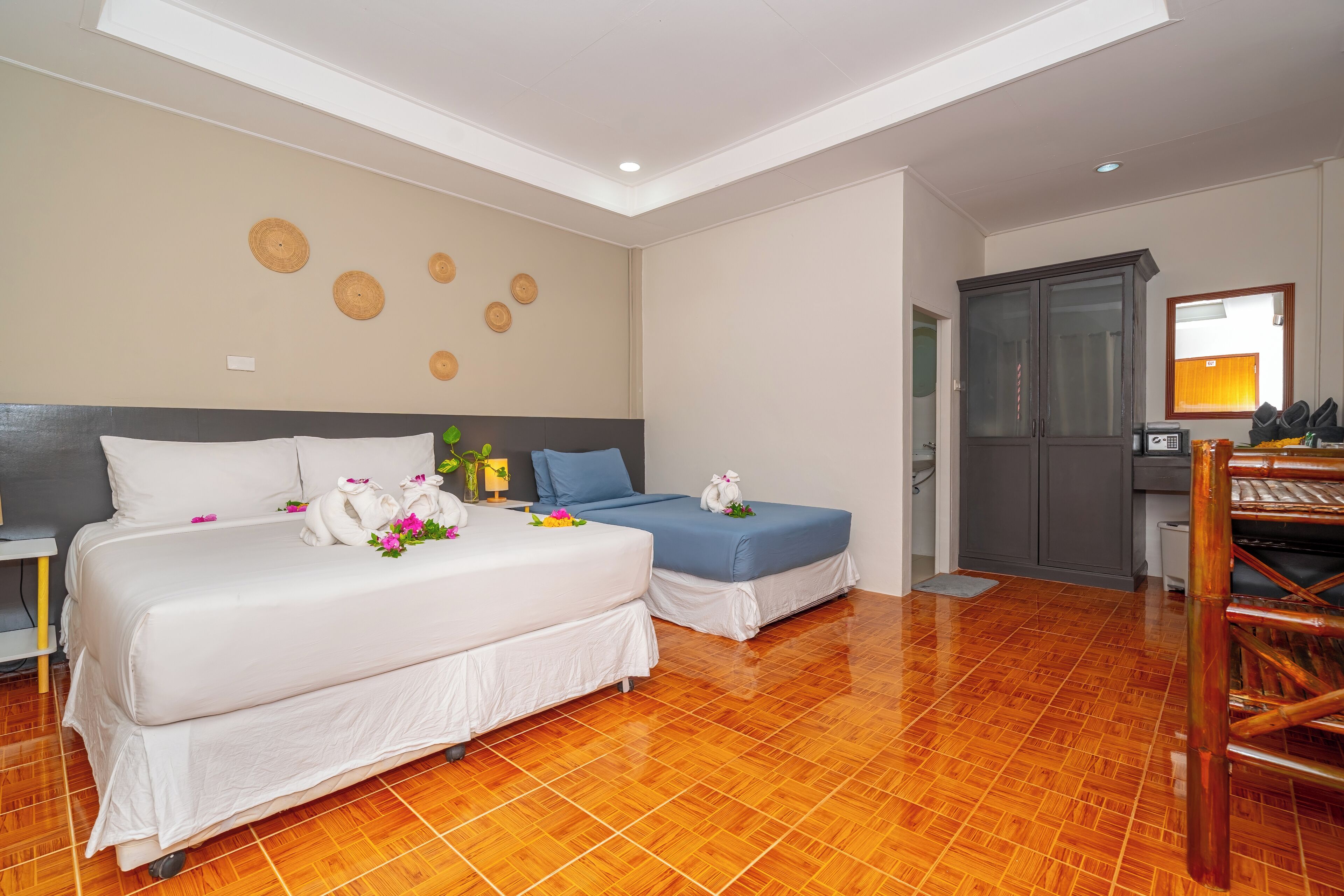 A hotel room with two beds, a wardrobe, and a bathroom.