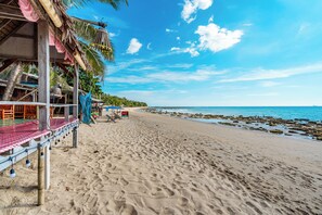 Una spiaggia con una struttura in legno, palme e un cielo azzurro intenso.