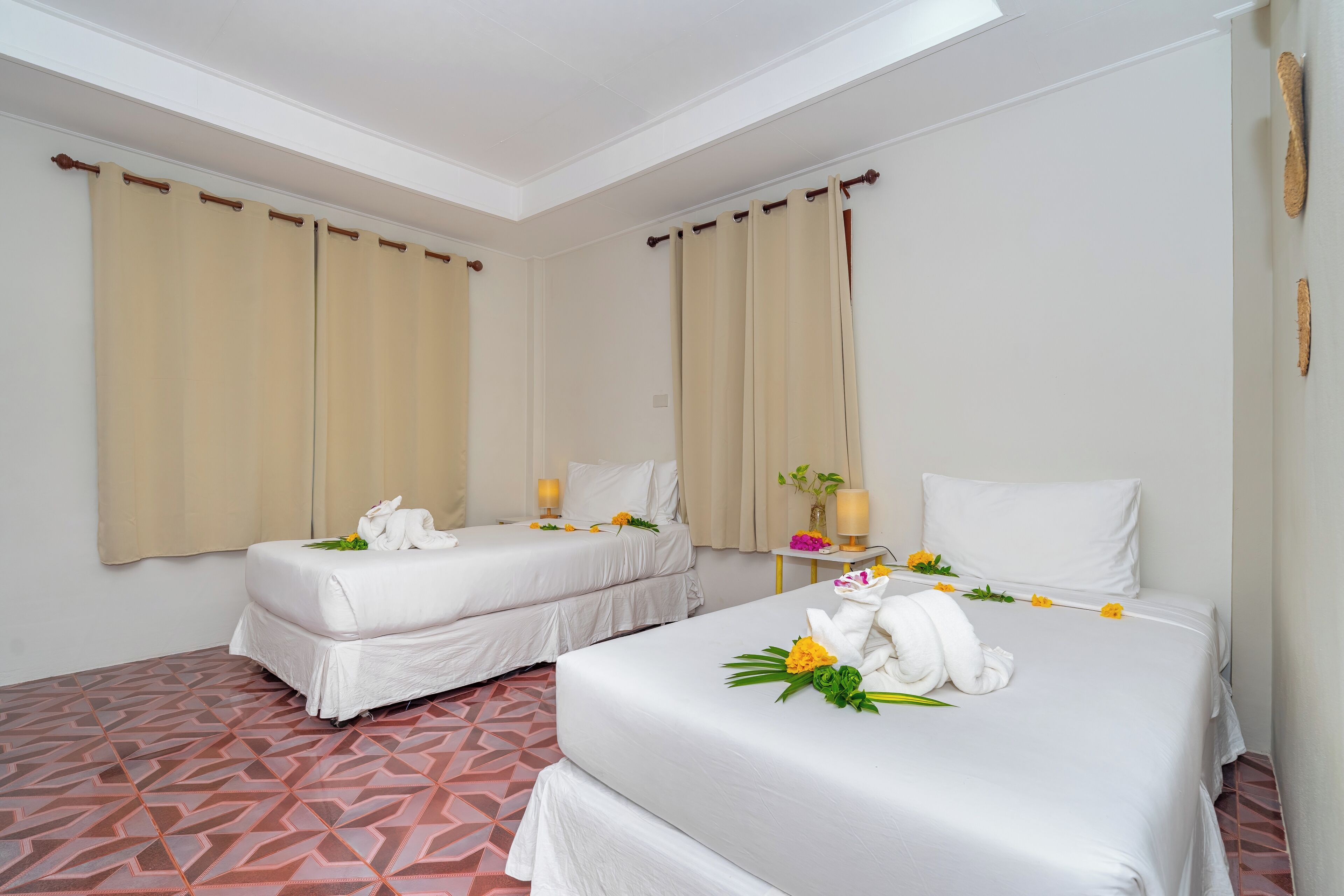 A hotel room with two beds, beige curtains, and a patterned floor.