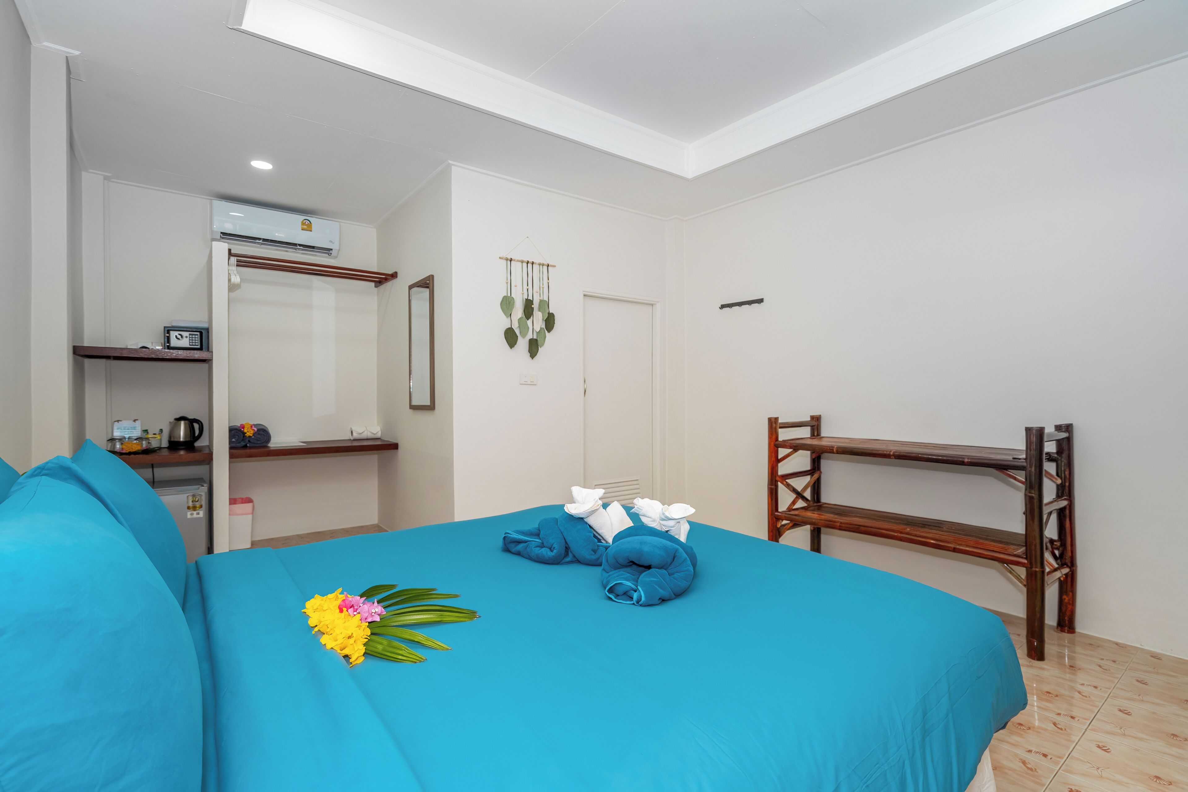 Ein Hotelzimmer mit einem Bett, einer hölzernen Bank, einer kleinen Küchenzeile und einem Spiegel.