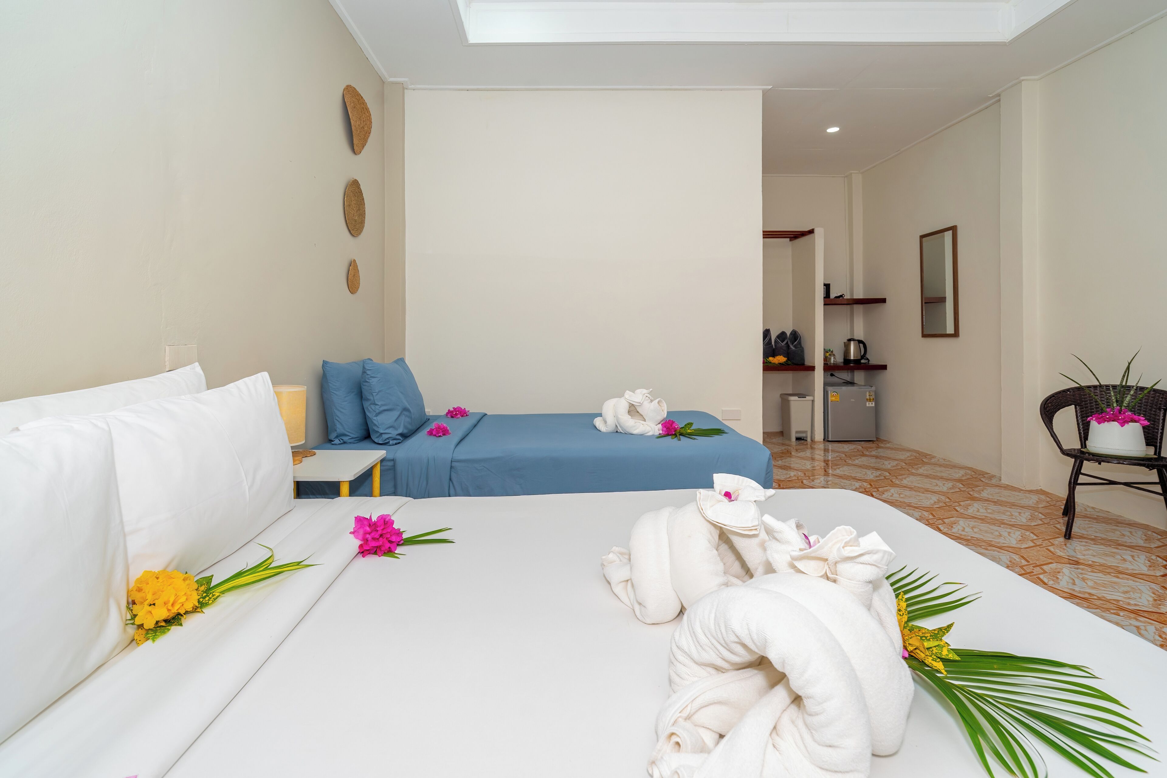 A hotel room with a bed, a sofa, a small table, and a chair. There are towels and flowers on the bed.