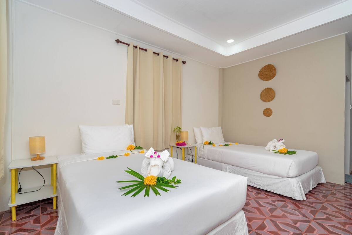 A hotel room with two beds, a small table with a lamp, and a decorative wall with circular patterns.