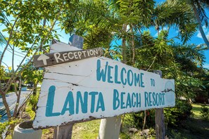 Segnaletica in legno con su scritto "Benvenuti al Lanta Beach Resort" e una freccia che indica la reception.