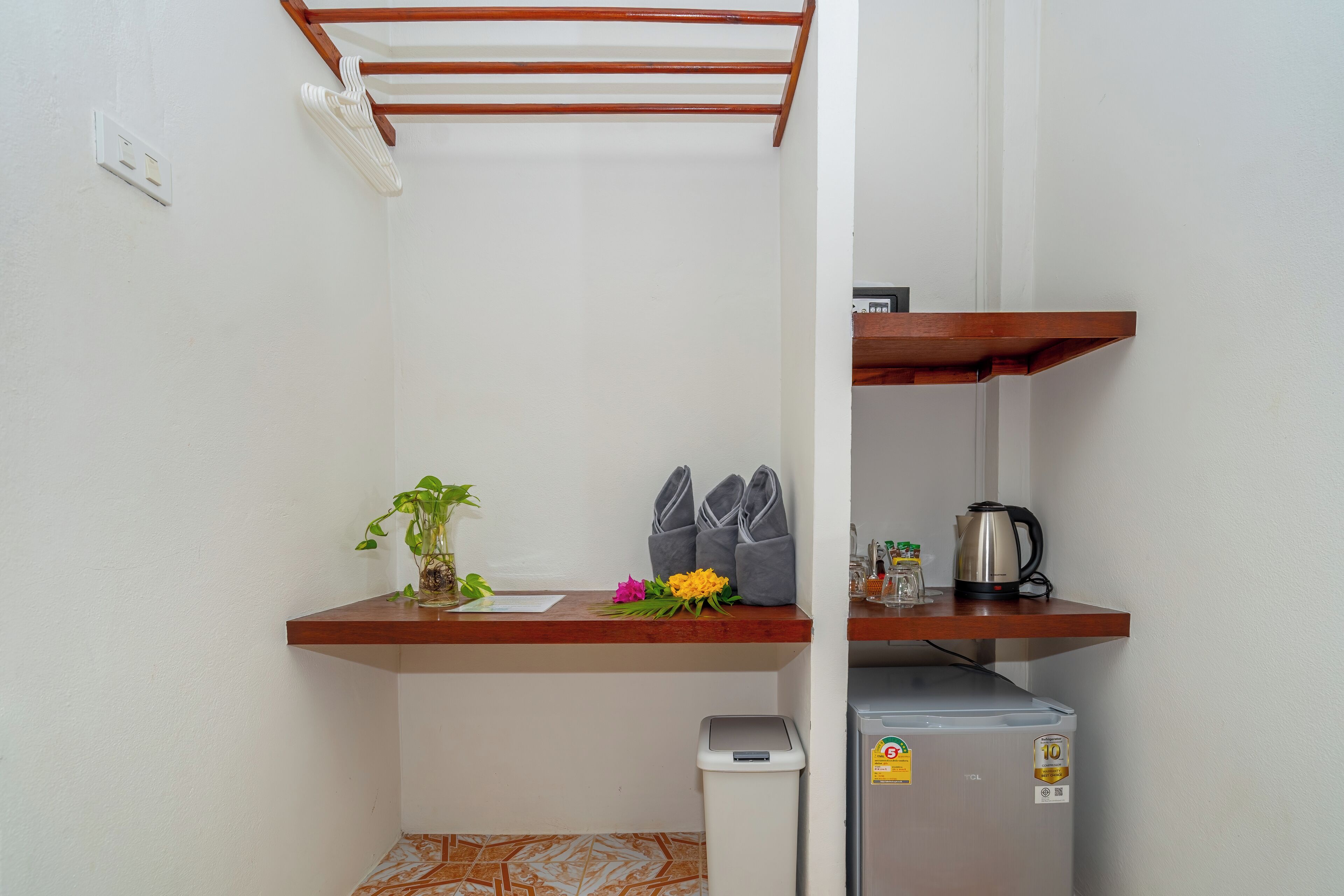 Cocina compacta con encimera de madera, un refrigerador pequeño, un cubo de basura y un estante con zapatos y una planta.