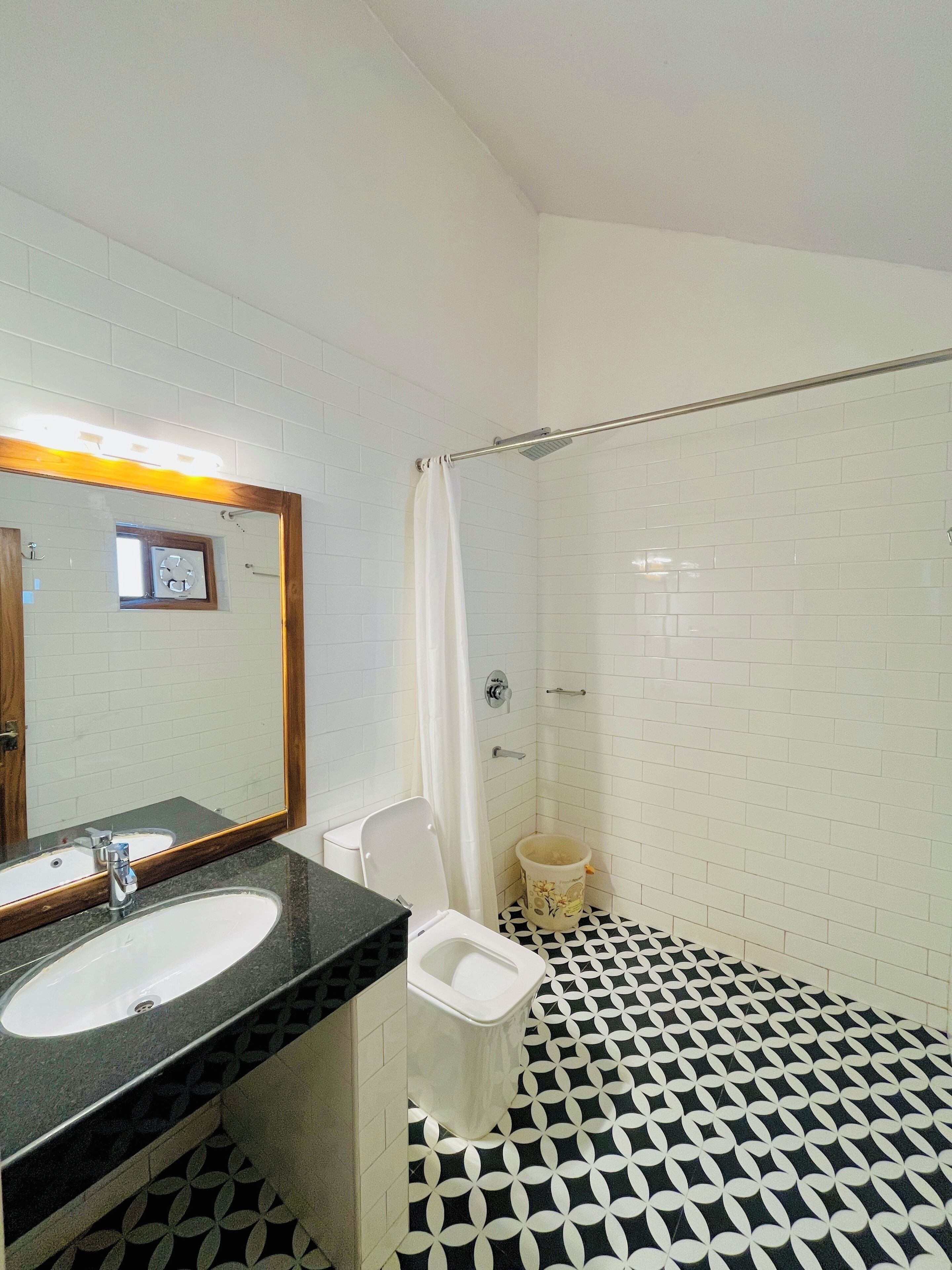A bathroom with a sink, mirror, toilet, and shower area.