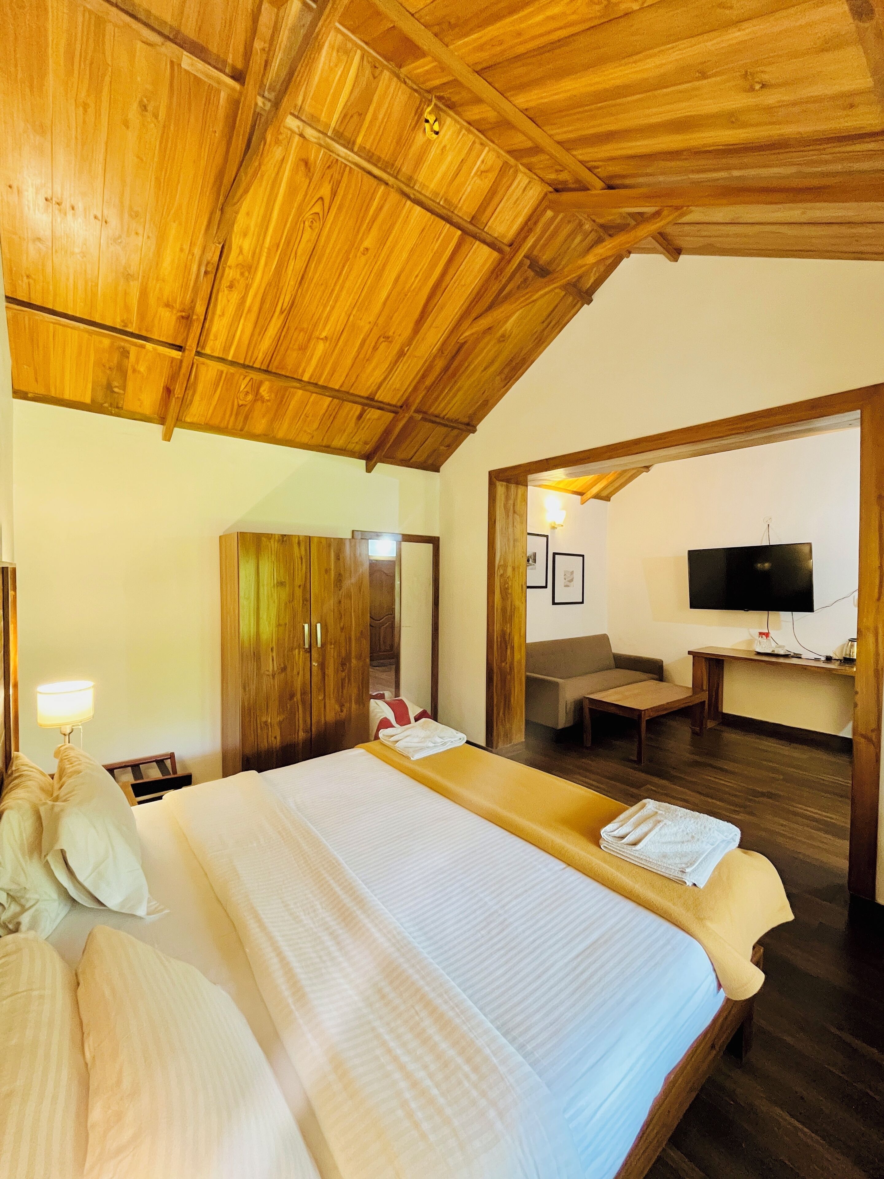 Ein Zimmer mit einem großen Bett, Holzboden und einem Schreibtisch mit Fernseher.