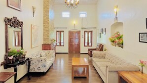 A spacious living room with two sofas, a wooden coffee table, and a chandelier. - BouganVilla (Ootacamund)