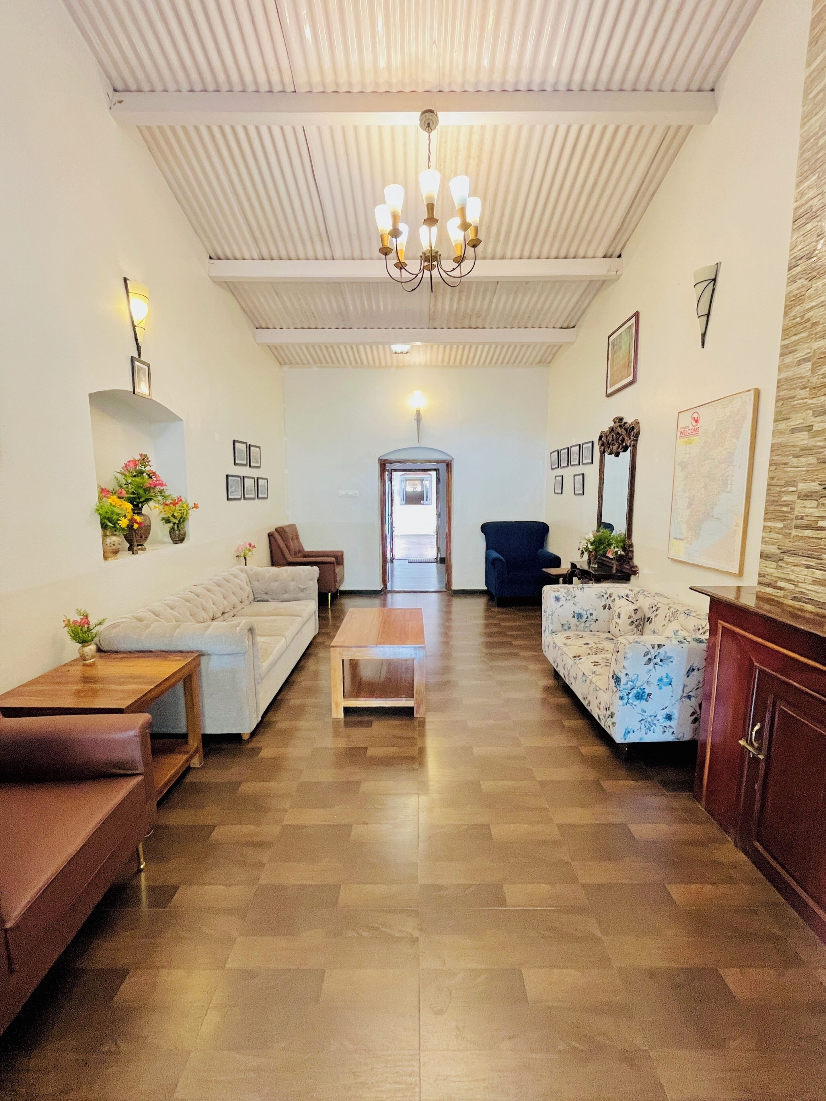 A spacious living area with a high ceiling, a chandelier, and a view into the hallway.