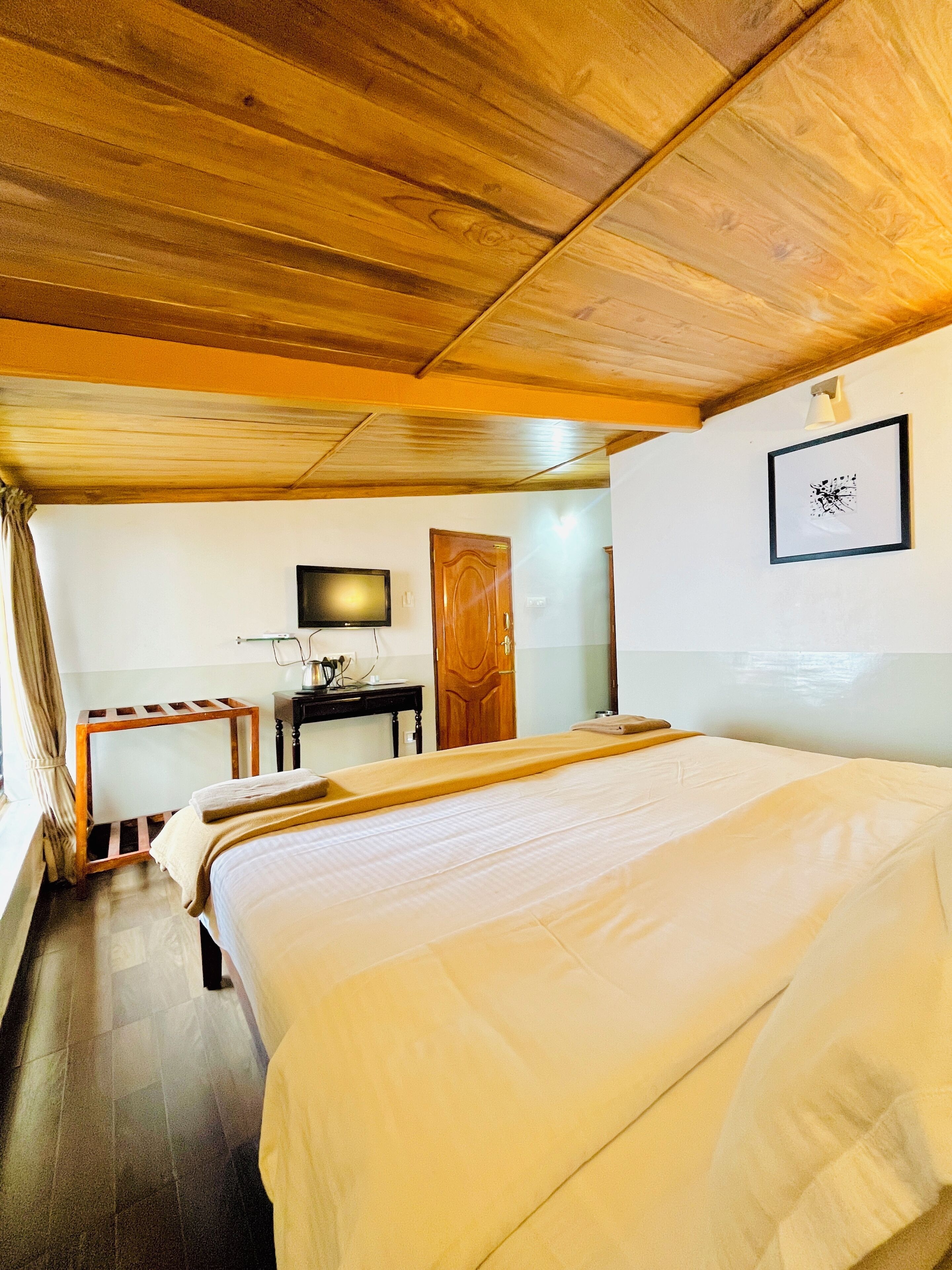Una habitación con una cama grande, un escritorio con una silla, un televisor y una puerta.