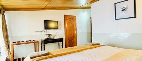 Una habitación con una cama grande, un escritorio con una silla, un televisor y una puerta.