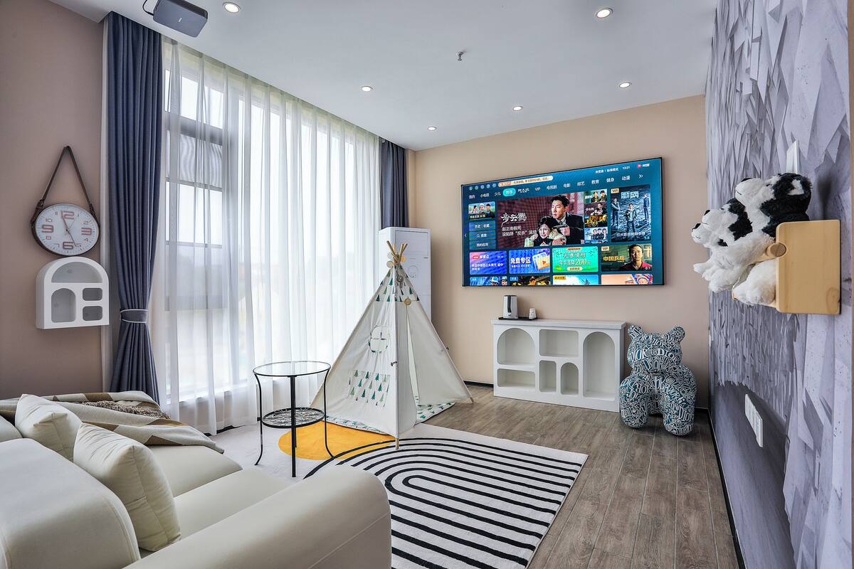 A modern living room with a sofa, a TV, a tent, and a bear decoration.
