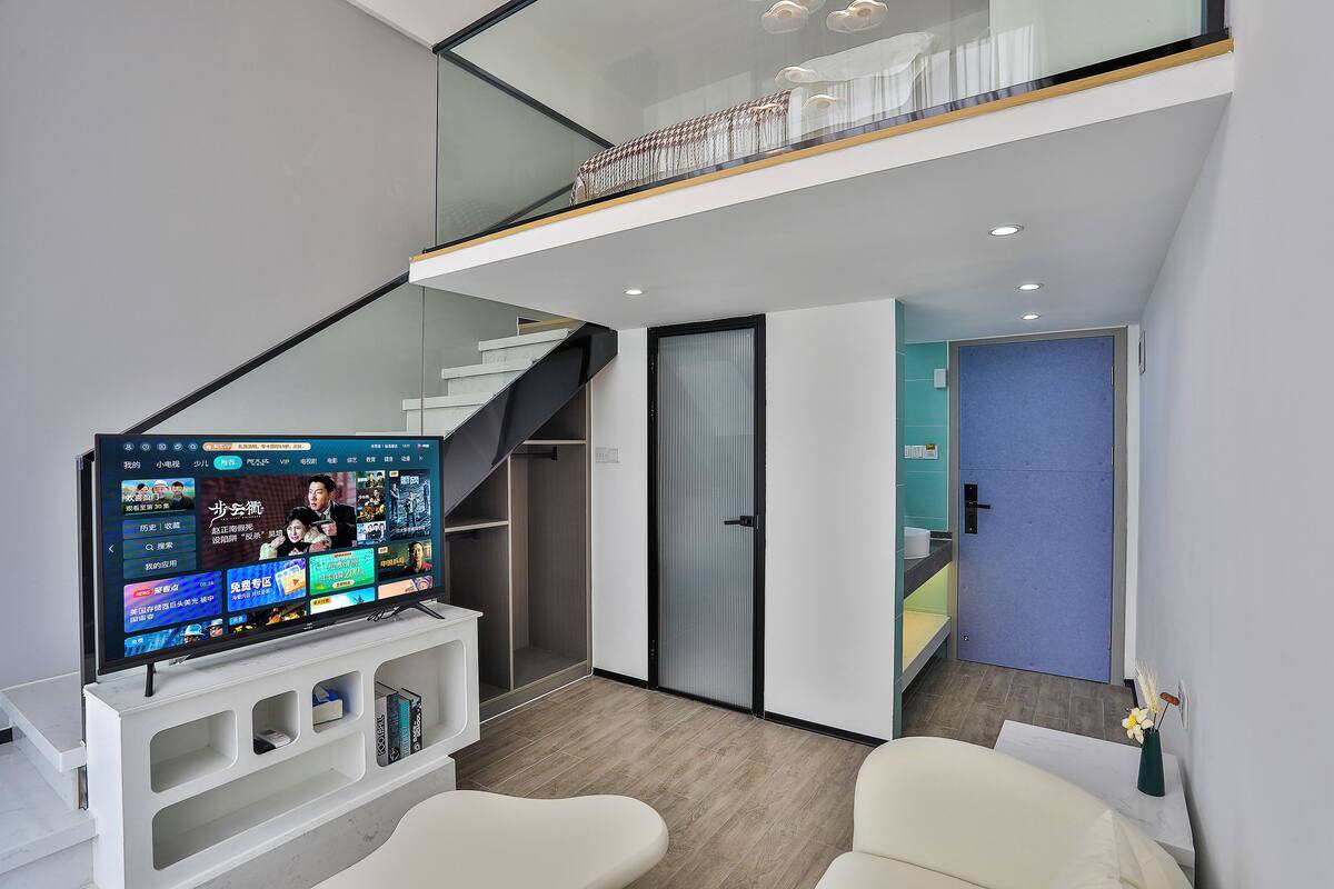 A modern interior with a flat-screen TV, a staircase, and a door.