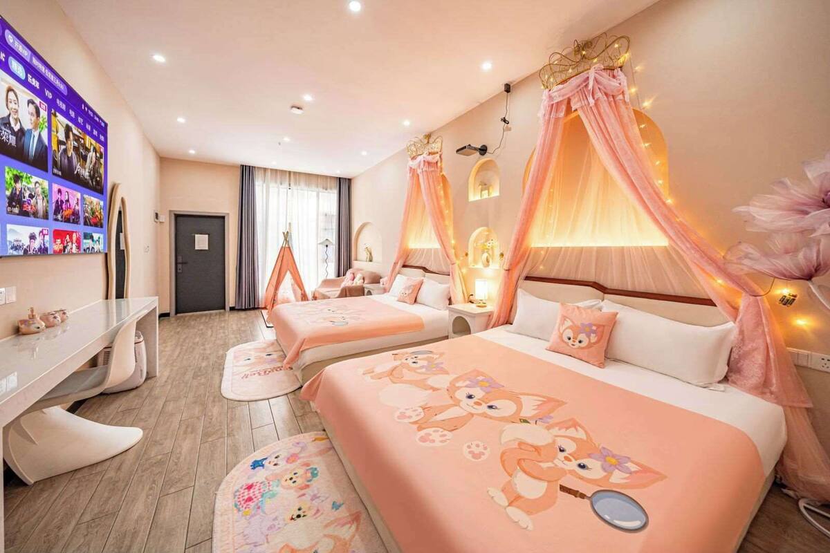 A hotel room with two beds, a desk, and a TV.