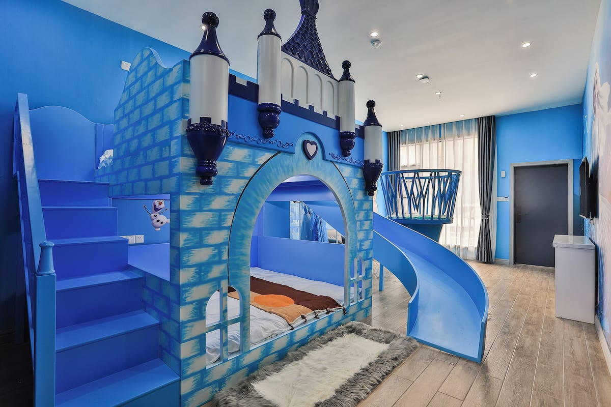 A bedroom with a castle-themed bed, a slide, and a staircase.