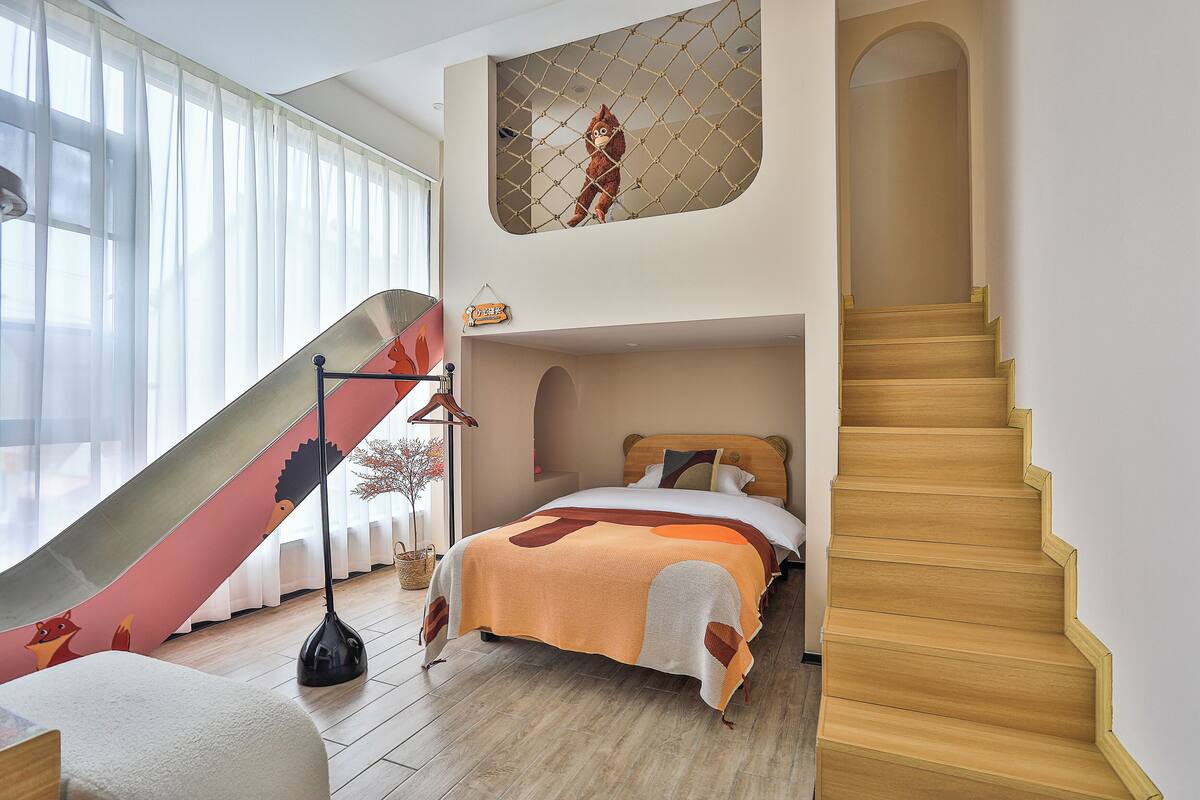 A bedroom with a bed, a staircase, and a window with curtains.