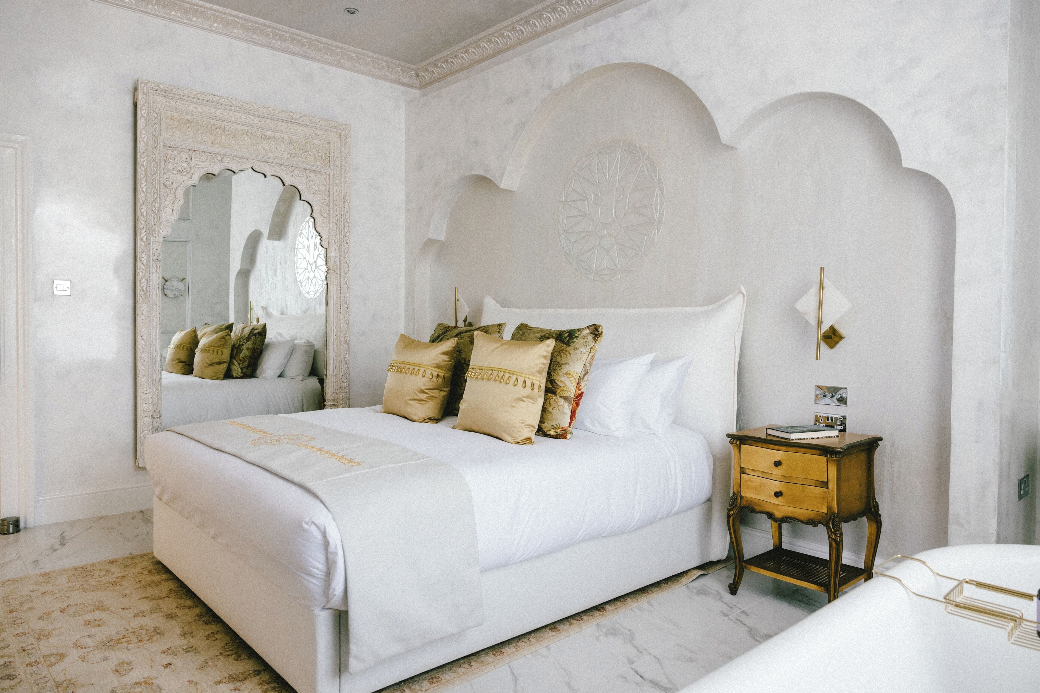 Une chambre à coucher avec un grand lit, une table de chevet et un miroir.