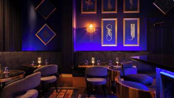A dimly lit bar area with tables, chairs, and framed calligraphy art on the wall.