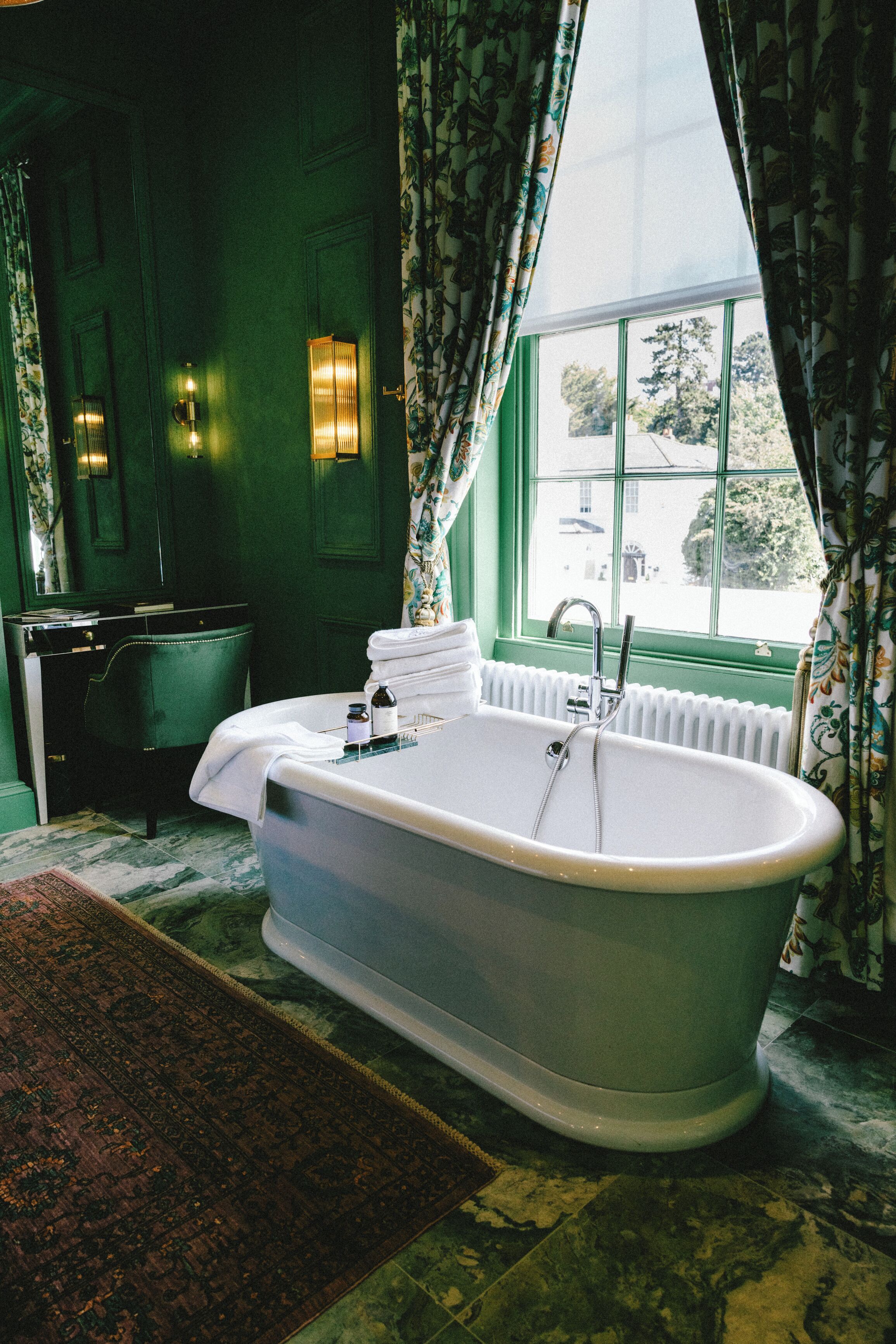 A bathroom with a freestanding bathtub, a radiator, and a window with curtains.