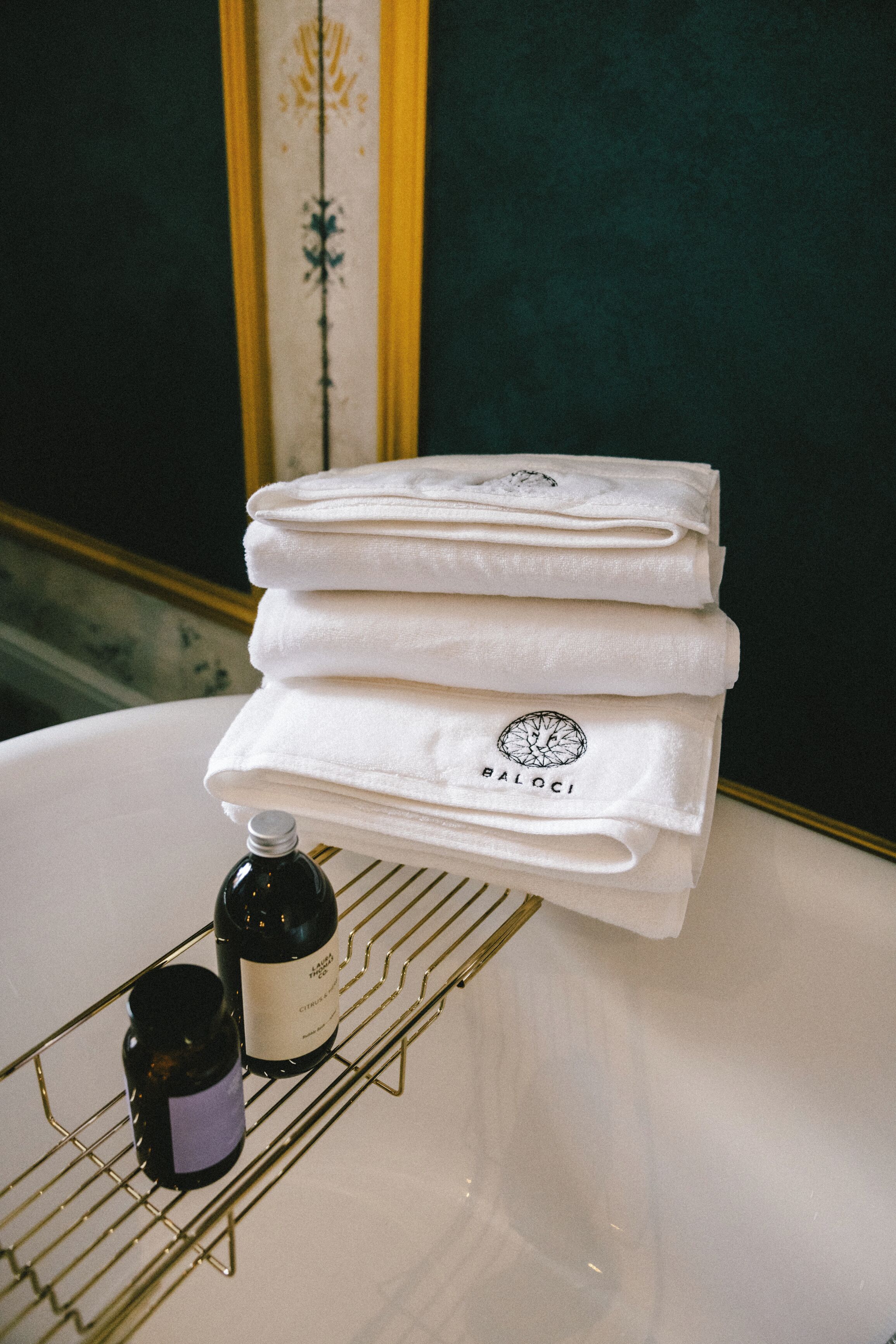 Une pile de serviettes blanches, portant un logo, est posée sur une baignoire blanche.