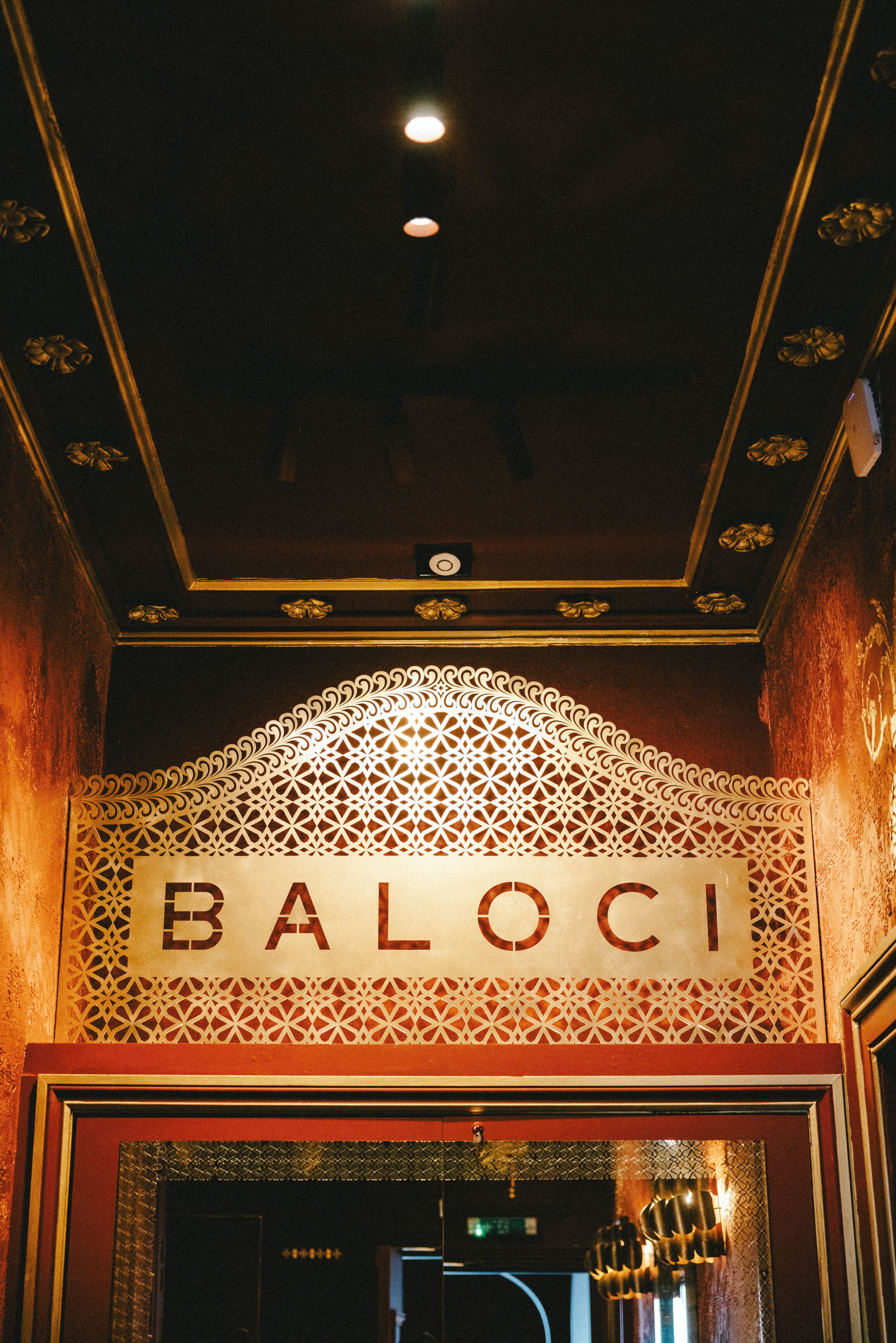 A sign with the word "BALOCI" in a decorative font, indicating the name of a location or establishment.