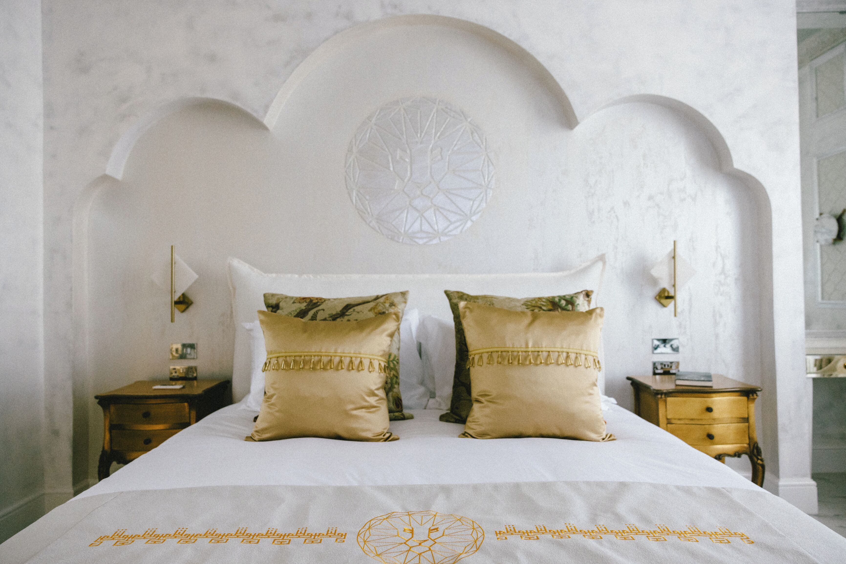 A bed with a white headboard, two decorative pillows, and a geometric wall design.